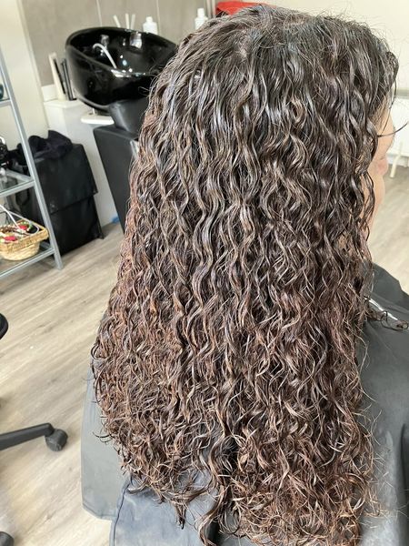 Long dark hair with a finished curly perm